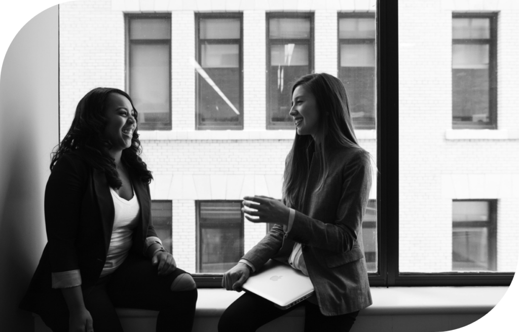 Two women in an office, talking and smiling